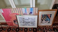 Three framed art pieces including pencil sketch and colorful prints