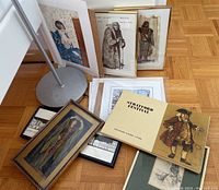 Photo showing the complete lot including two main framed Stratford Festival costume sketches in metal frames, assorted smaller framed and unframed art pieces, a Stratford Festival box containing various costume sketches and prints.