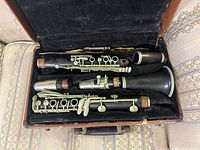 Internal view of open case showing disassembled clarinet sections: upper joint, lower joint, barrel, bell and keys