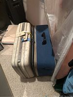 Silver and blue vintage suitcases side by side on carpeted floor