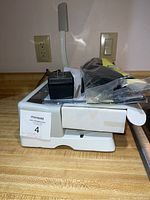 Side view of CoilPro manual binding machine with power adapter and package of coils on top