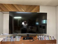 Front view of the Hisense 65-inch LED TV on a stand, screen is off, with collars under the TV on the surface.