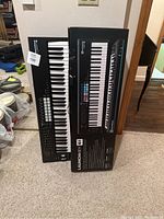 Photo of two boxed Novation Launchkey 61 keyboards standing upright showing front panel and packaging.