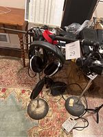Photo showing headphones on metal stand with round heavy base on patterned rug next to small wooden table