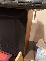 Speaker positioned next to audio equipment showing wood veneer side panel and black grille with ADS logo