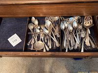 Drawer containing mixed tarnished sterling silver flatware and serving utensils