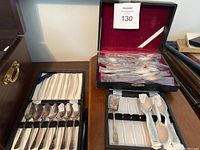 Overview of three fitted cases with assorted sterling spoons