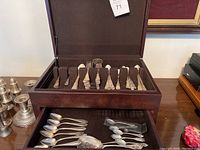 Open cherry wood box showing top and bottom trays with silver flatware and serving pieces