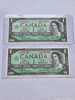 Front sides of two Canadian $1 bills from 1967 Centennial series showing Queen Elizabeth II and serial numbers.