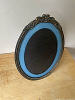 Front view of the ornate oval photo frame showing blue inner border and decorative top design.