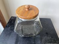Front view of the empty glass cookie jar with wooden lid showing hexagonal shape