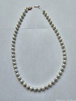 Full view of pearl necklace laid flat on white background