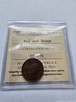 Front side of the 1945 Canadian penny showing grading certificate with MS-63 grade and red and brown comments.