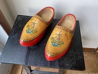 Pair of vintage Holland wooden shoes with windmill design and red painted accents, shown from the top angle.