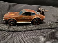 Side view of one copper-colored Hot Wheels Mighty Maverick car showing red line tires and rear spoiler
