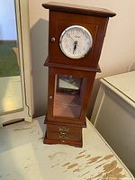 Full front view of vintage wooden jewelry box clock showing clock face and glass cabinet door with floral etching.