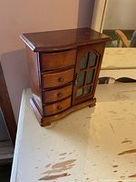 Full view of vintage wooden jewelry box stand with drawers and glass door.