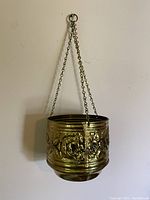 Front view of the vintage metal hanging pot showing hanging chains and embossed floral details.