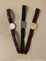 Three watches laid flat front view showing dials and straps