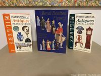 Photo of the three antique research guidebooks standing upright showing front covers; two Miller's guides and one Royal Doulton guide.