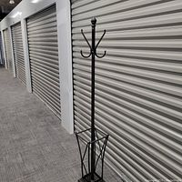 Full view of the black metal coat rack with umbrella stand in a storage hallway.