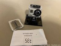 GoPro camera in waterproof housing with printed settings menu manual.