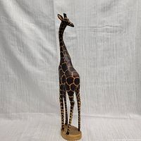 Front view of a tall giraffe figurine carved from Besmo wood, showcasing the detailed paint spots and smooth natural wood base.