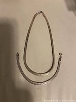 Two Italian sterling silver chain and bracelet laid out on a surface, showing design and size difference.