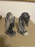 Pair of marble knight horse head bookends facing forward, showing detailed carved horse heads and manes.