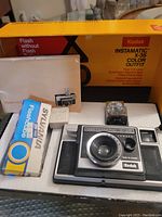 Full lot including Kodak Instamatic X-35 camera, original yellow box, user guide, flashbulb pack, and detachable flash unit.
