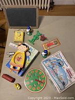 Overview image of the vintage toys laid out on table, showing main items including Fisher Price clock toy, green army men, Donald Duck shakers, The Lucky Animals game, toy phone, and other small toys.