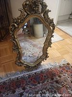 Full front view of ornate plaster mirror leaning against wall