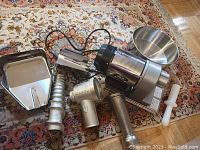 All components laid out on patterned rug: motor housing, funnel, auger, cast aluminum housing, tray, pusher and filter