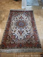Full view of rug on parquet floor showing central design and fringe ends