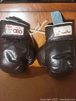 Pair of vintage brown leather boxing gloves displayed from front, showing lace-up strings and brand patches on wrist band.