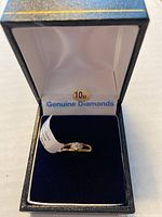 Front angle of 10Kt yellow gold baby ring with diamond centerpiece in original jewelry box showing authenticity tag.