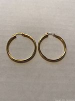 Pair of 10Kt yellow gold hoop earrings laid flat showing full shape and clasp mechanism.