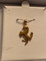 Front view of 10Kt yellow gold horse-shaped charm pendant in box, showing detail of horse figure and bail.