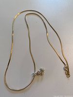 Full view of the 16-inch serpentine chain with attached flower charm featuring small clear stones.