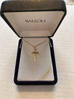 Image of 14Kt yellow gold cross necklace in Ballou branded jewelry box showing the pendant and chain.