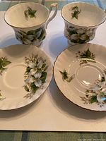 Two Royal Albert Trillium cups and their matching saucers showing floral pattern and gold rim