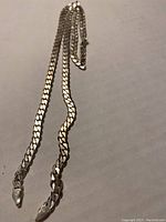 Full view of men's heavy silver link chain showing length and chain links.