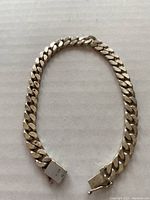 Silver bracelet laid flat on a neutral surface showing the seven large, flat interlocking links.