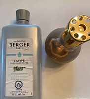 Photo showing the gold tone Lampe Berger lamp next to the silver 1L Fresh Eucalyptus refill bottle with label visible