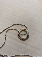 Close-up of the sterling silver round floating LOVE charm pendant with engraved text.