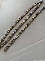 Three-piece set consisting of one necklace and two bracelets laid flat, showing two-tone silver and gold-tone sectioned pattern.