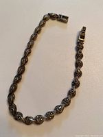 Full view of the ornate silver bracelet displaying its decorative twisted design and clasp.