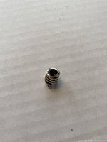 Top-down view of the sterling silver coiled snake charm bead on white background showing circular hole for threading.