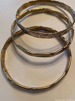 Three silver bangle bracelets arranged on flat surface, showing varying widths and textures, all stamped .925 Mexico.
