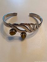 Front view of the silver adjustable bracelet showing the two amber-colored stones and leaf design.